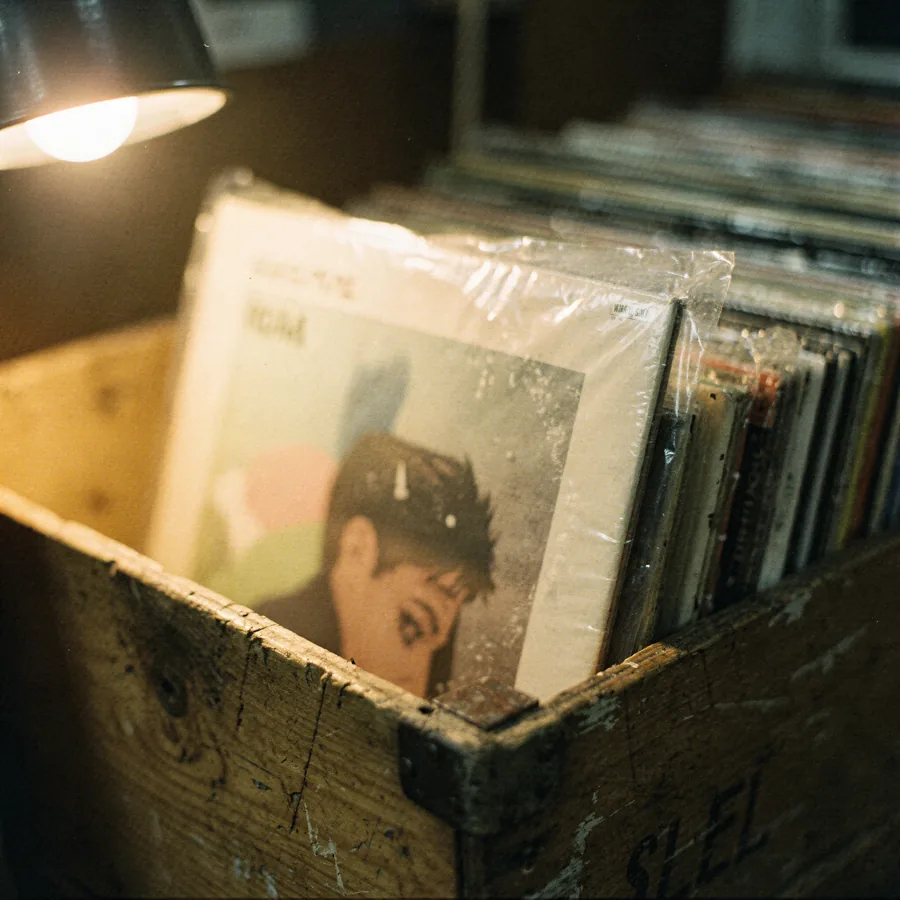 A vinyl LP being pulled halfway out of a wooden record crate