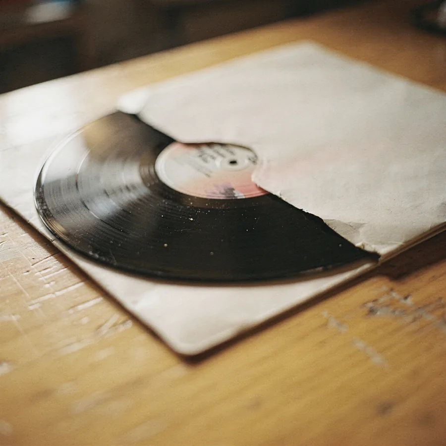 A black vinyl record halfway out of its paper inner sleeve