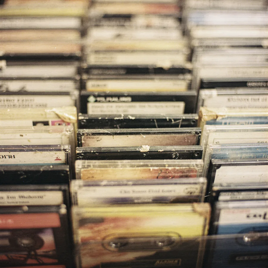 Pre-recorded cassette tapes standing upright in a retail rack