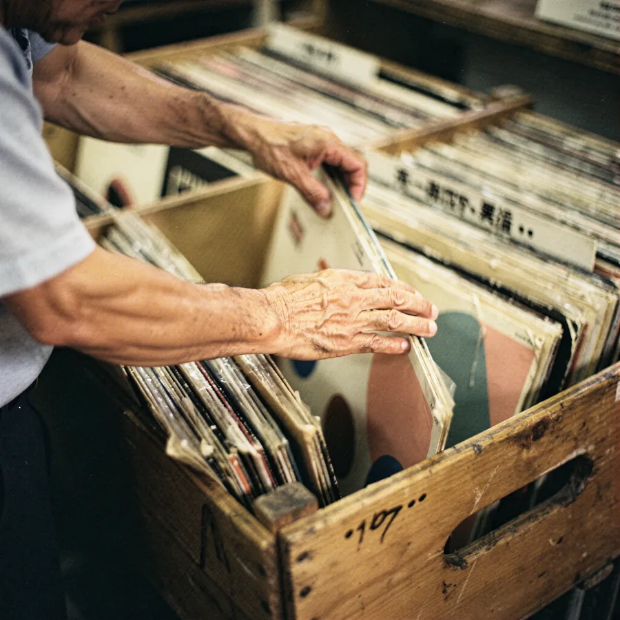 Hands flipping through vinyl records in a wooden crate